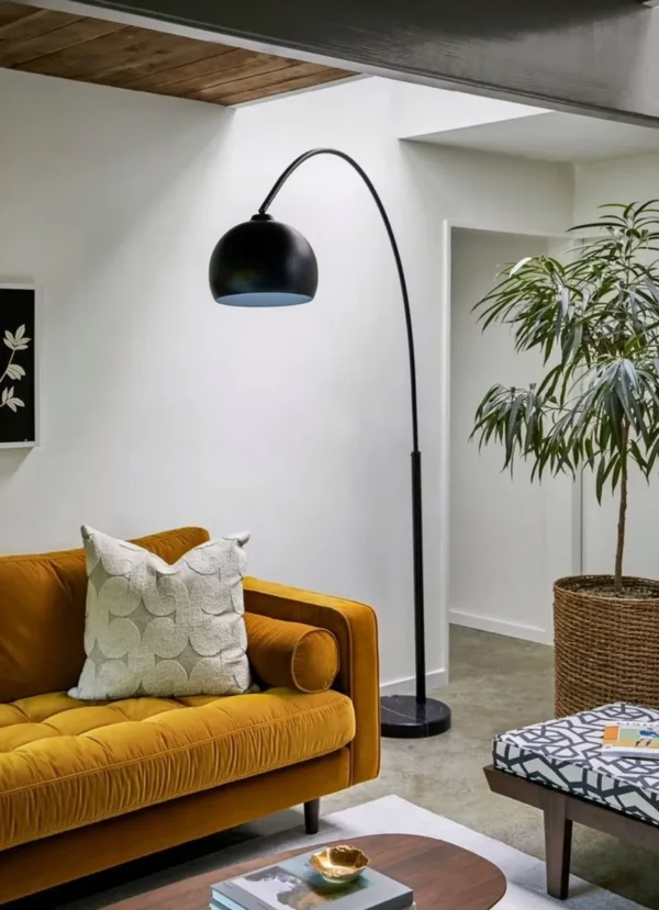 overhead Floor lamp with long bent stand black beside the couch